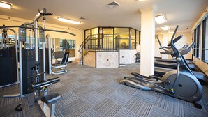 A gym with various exercise equipment, a staircase, and a carpeted floor. - Stay Together Suites | Strip Condo PH (Las Vegas)