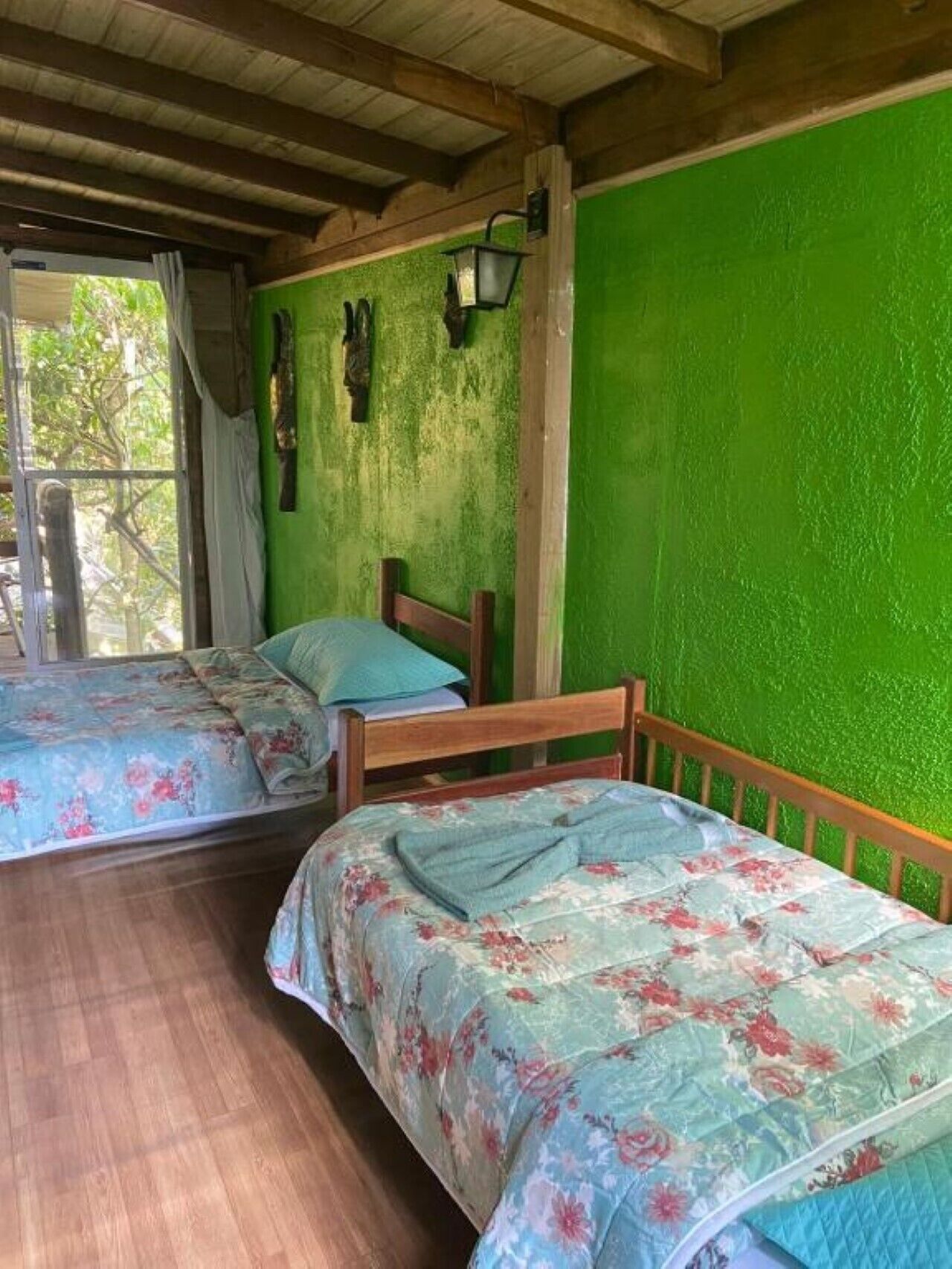 A room with two wooden beds, green walls, and a wooden floor.