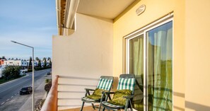 A balcony with two chairs and a view of the street.