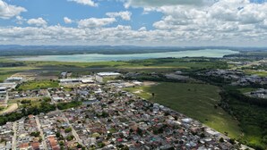 Une vue aérienne d’une ville, avec des quartiers résidentiels, des bâtiments industriels et une vaste étendue d’eau en arrière-plan.