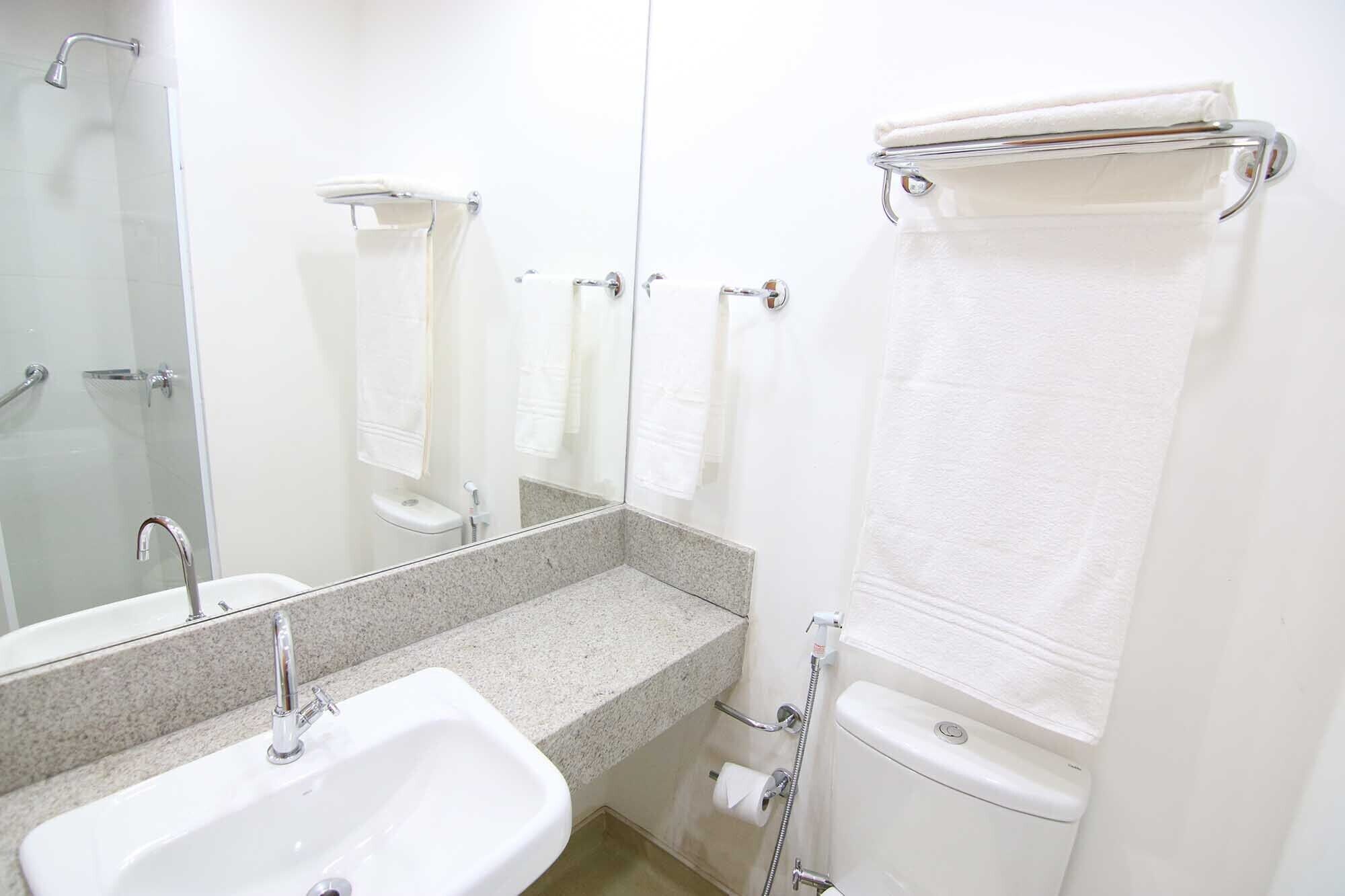 Een badkamer met een wastafel, spiegel, douche en toilet.