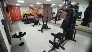 Une salle de sport équipée de tapis de course, de vélos elliptiques et de matériel de musculation.