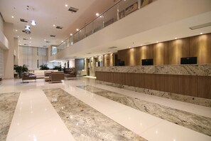A spacious lobby with a marble floor, a reception desk with a wooden finish, and a seating area with sofas. - Samba Linhares (Linhares)