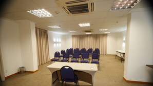 Une salle de conférence avec une longue table, plusieurs chaises et une petite table en arrière-plan.