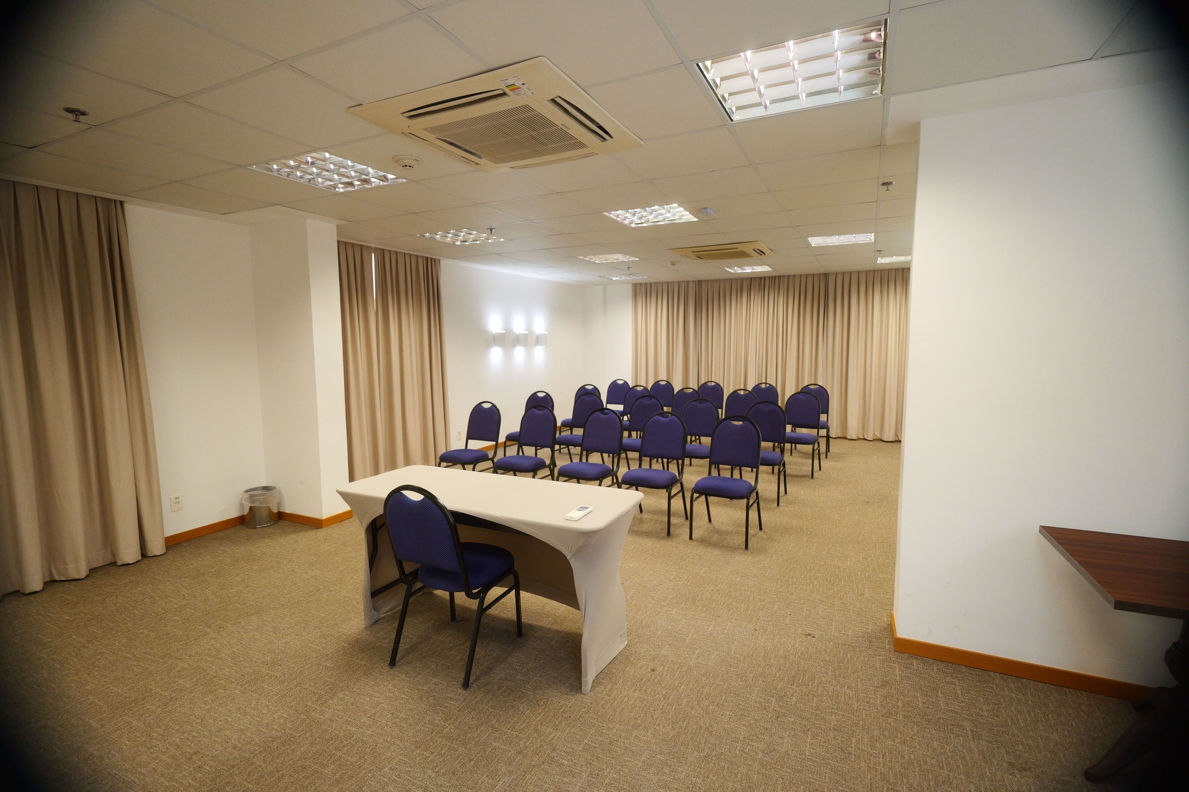 Un salón de conferencias con una larga mesa, varias sillas y suelo alfombrado.