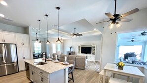 Une cuisine moderne dotée d’un îlot central, d’appareils électroménagers intégrés, de luminaires suspendus et d’un coin repas offrant une vue agréable.