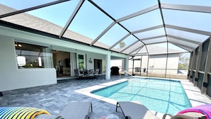 Un espace extérieur avec une piscine, des chaises longues et un patio couvert.