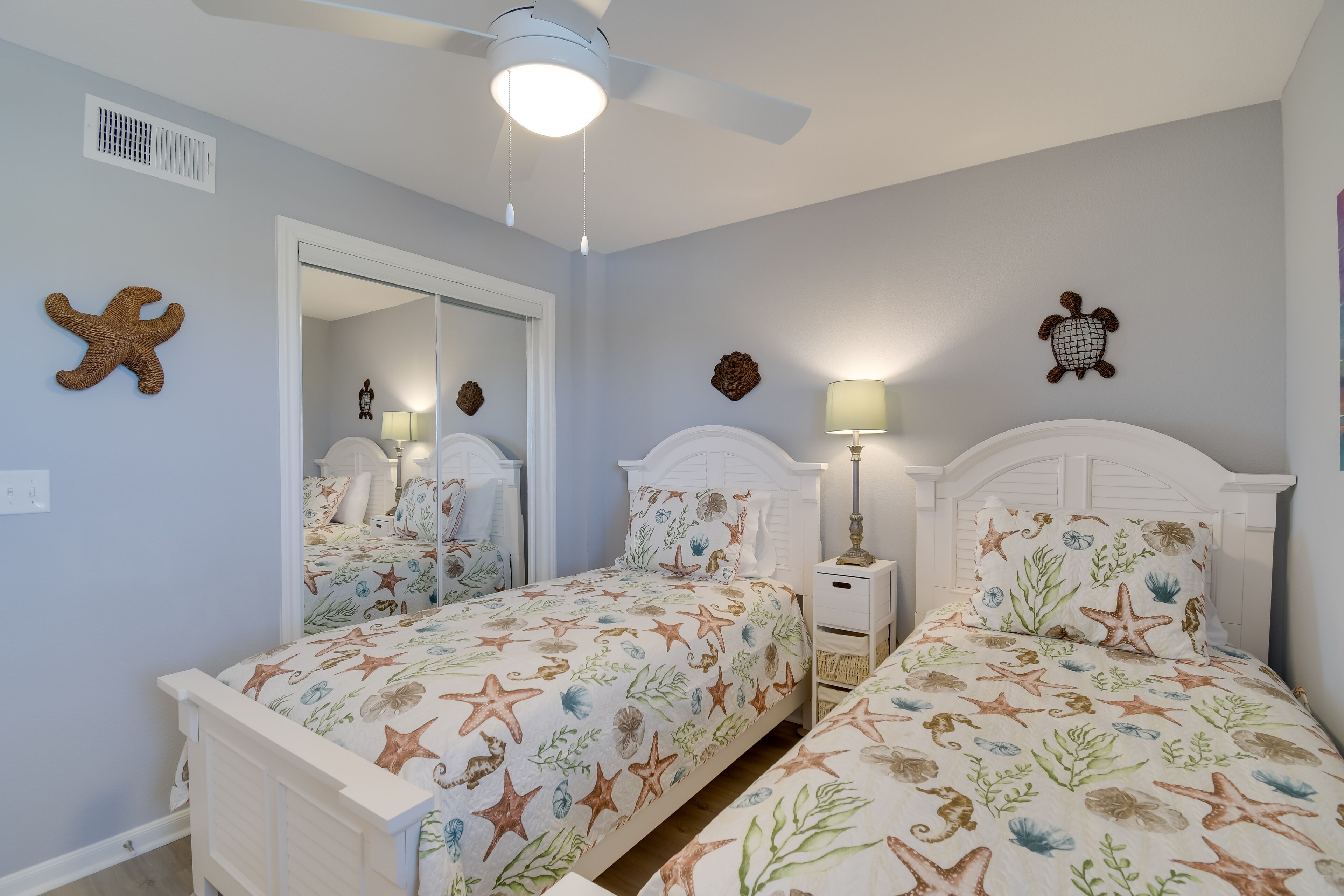 Ein Schlafzimmer mit zwei Betten, einem Deckenventilator und Wanddekoration.
