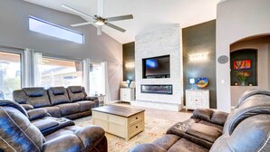A modern living room with leather sofas, a flat-screen TV, and a fireplace.