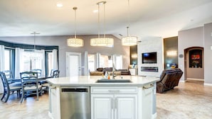 A spacious kitchen with a central island, a dishwasher, and a dining area with chairs and a table.