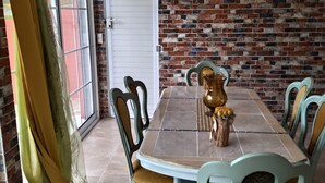 A dining area with a brick wall, a white door, and a table set with chairs. - Nice apartment 8 minutes from la meynard hospital (Saint-Joseph 97212)