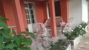 A covered outdoor seating area with white wicker chairs and a stone-tiled floor. - Nice apartment 8 minutes from la meynard hospital (Saint-Joseph 97212)