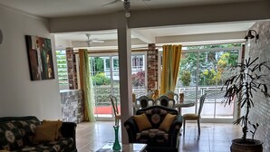 A spacious living room with a sofa, a coffee table, and a chair. There is a balcony with a view of greenery. - Nice apartment 8 minutes from la meynard hospital (Saint-Joseph 97212)