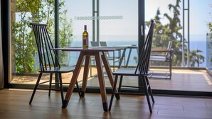 Een moderne eetruimte met een tafel en stoelen, een fles wijn en uitzicht op de oceaan.