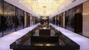 A hotel lobby with a central water feature, chandeliers, and decorative wall patterns. - Longchang Holiday Hotel (Tang County)