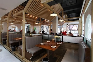 A restaurant interior with booths, tables, and a high ceiling with wooden beams. - Longchang Holiday Hotel (Tang County)