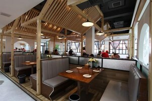 A restaurant interior with booths, tables, and a high ceiling with wooden beams.