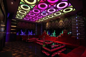 Un espace détente avec des canapés rouges et un sol à motifs, agrémenté d’un plafond au design géométrique.
