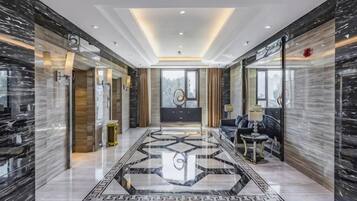 Un vestíbulo de hotel con piso de mármol, una recepción y una zona de estar.