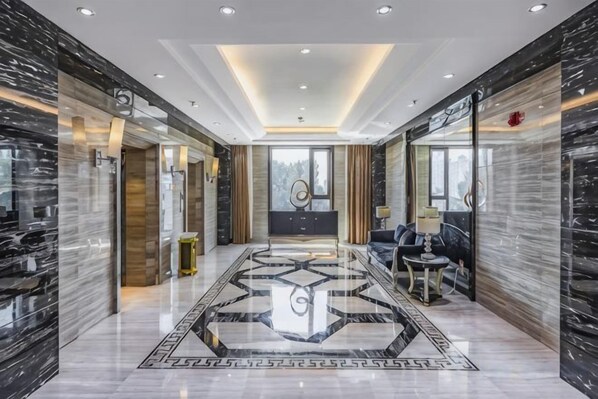 Un hall d’hôtel avec un sol en marbre, un comptoir d’accueil et un espace salon.