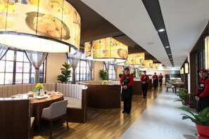 A restaurant with booths, a long counter, and staff in red uniforms. - Longchang Holiday Hotel (Tang County)