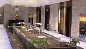 A modern lobby with a central water feature, a clock, and a reception desk. - Longchang Holiday Hotel (Tang County)