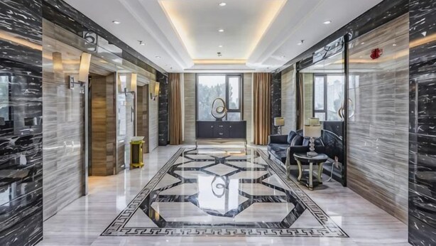 A hotel lobby with a marble floor, a reception desk, and a seating area. - Longchang Holiday Hotel (Tang County)