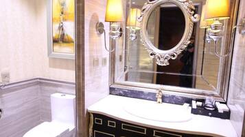 A bathroom with a marble vanity, a large ornate mirror, and wall-mounted sconces.