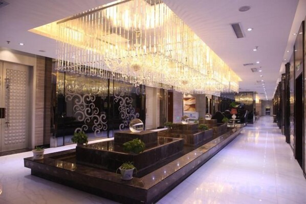 A hotel lobby with a reception desk, decorative lighting, and a long corridor.