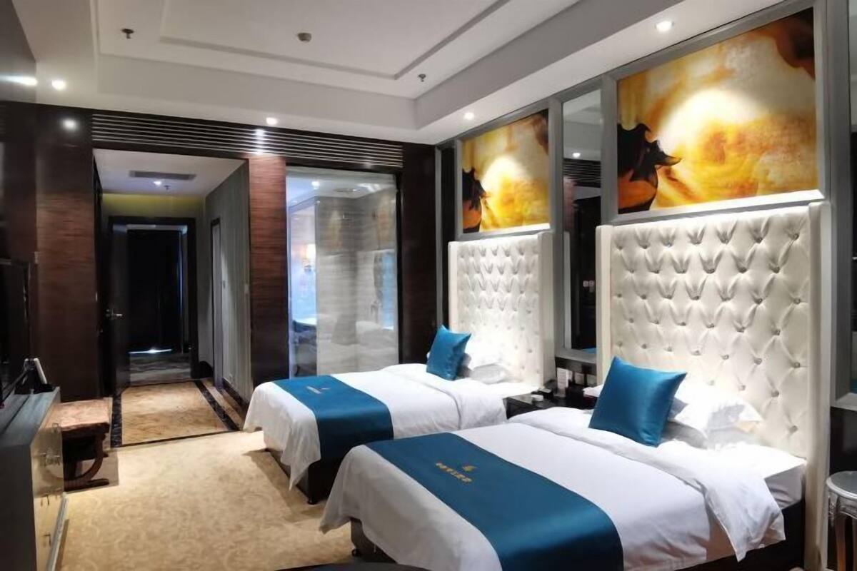 A hotel room with two beds, a large mirror, and a view of the city.