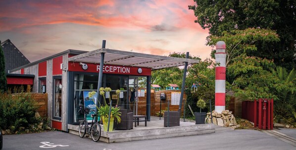 A reception area with a sign, a bicycle, and a covered seating area.