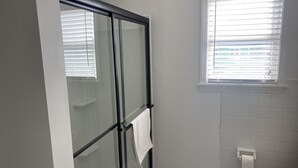 A bathroom with a glass shower enclosure, a toilet, and a window with blinds. - Hatteras Village *** Southside 3 *** (Hatteras)