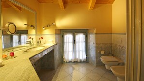A bathroom with a wooden ceiling, a large mirror, a sink with a vase of flowers, and two toilets. - THE WAVE :: APARTMENT (Lezzeno)