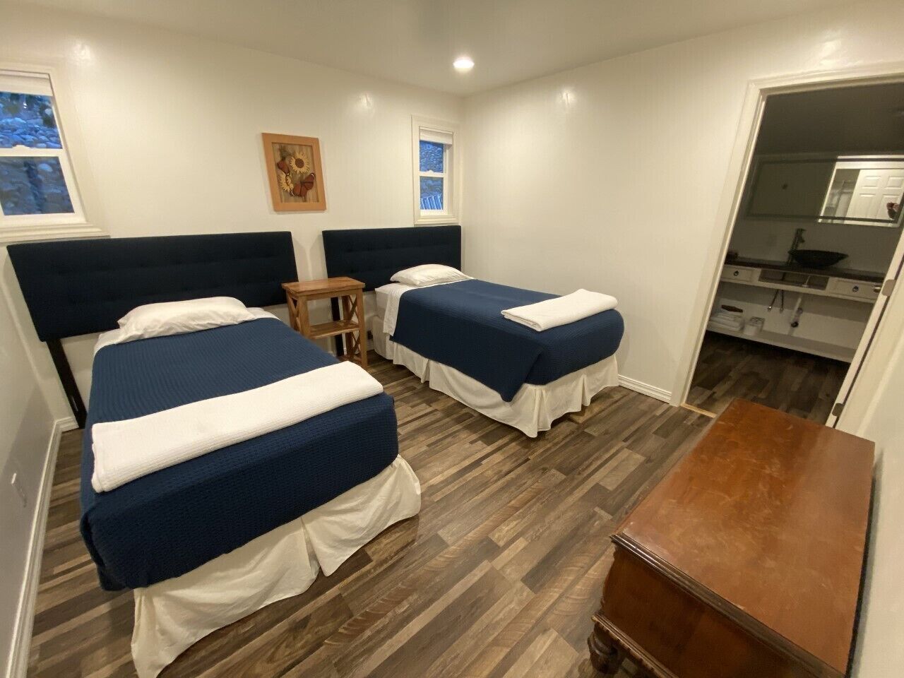 Habitación de hotel con dos camas, una mesa de madera y un pequeño rincón de descanso.