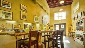 A spacious kitchen with wooden chairs, a long counter, and various framed artworks on the walls. - Strawhouse Resorts (Big Bar)