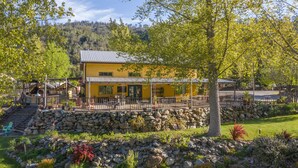 A yellow building with a patio area, surrounded by a stone wall and greenery. - Strawhouse Resorts (Big Bar)