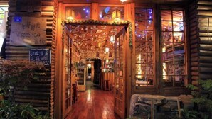 A cozy log cabin-style building with a wooden interior, a stone wall, and a sign that reads "A GOOD YEAR." - A Good Year (Fenghuang County)
