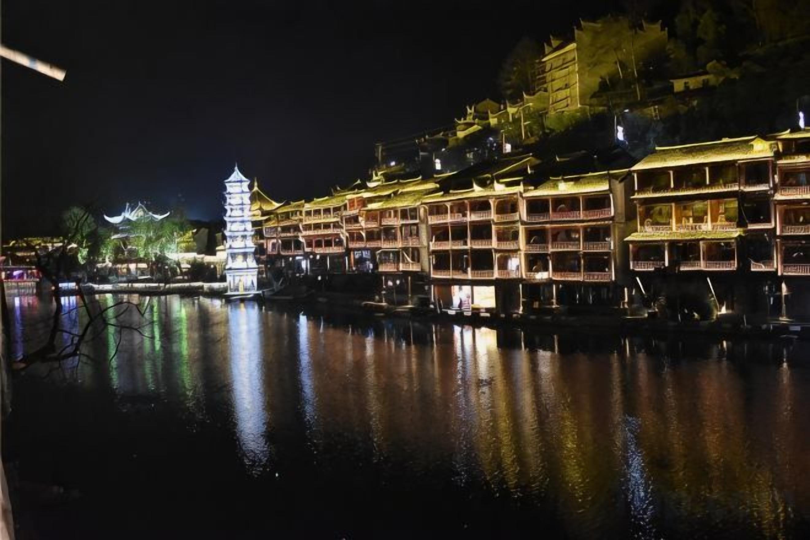 Un edificio tradicional de varios pisos y balcones, ubicado junto a una masa de agua por la noche.
