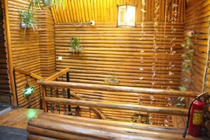A log cabin interior with a wooden staircase, a fire extinguisher, and hanging plants. - A Good Year (Fenghuang County)
