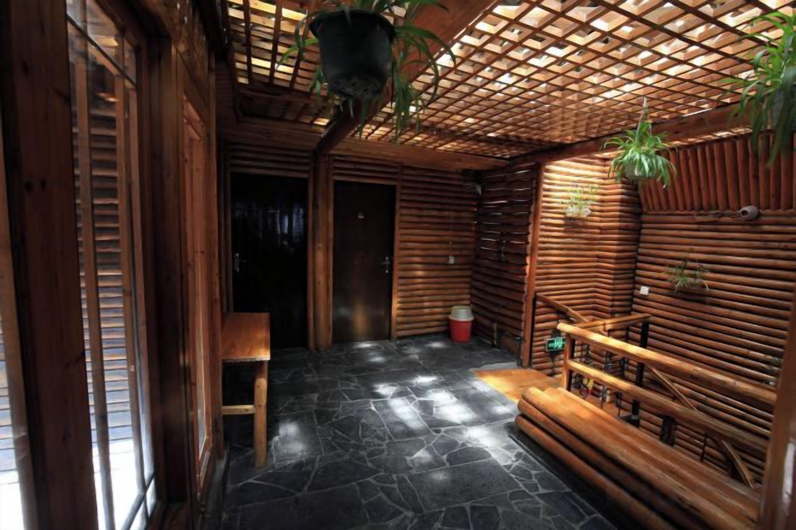 A wooden interior with a stone floor, a bench, and a hanging plant.