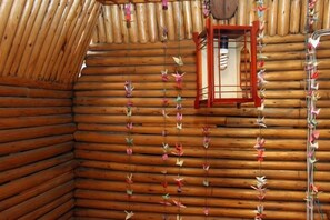 A log cabin interior with a window and hanging decorations. - A Good Year (Fenghuang County)