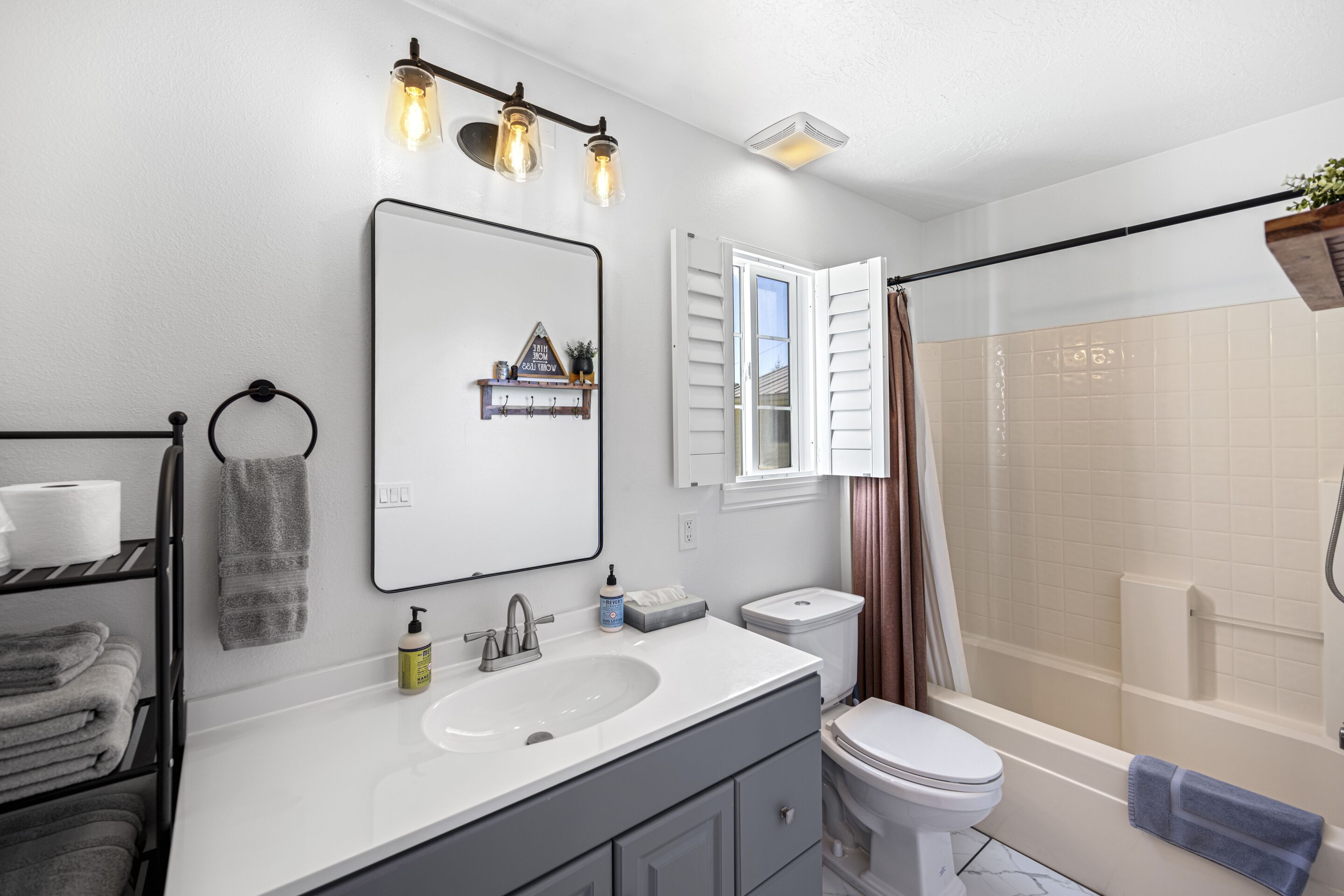 Une salle de bain moderne avec un lavabo blanc, un meuble-lavabo et des toilettes. On y trouve une douche avec une porte en verre et un porte-serviettes avec des serviettes.