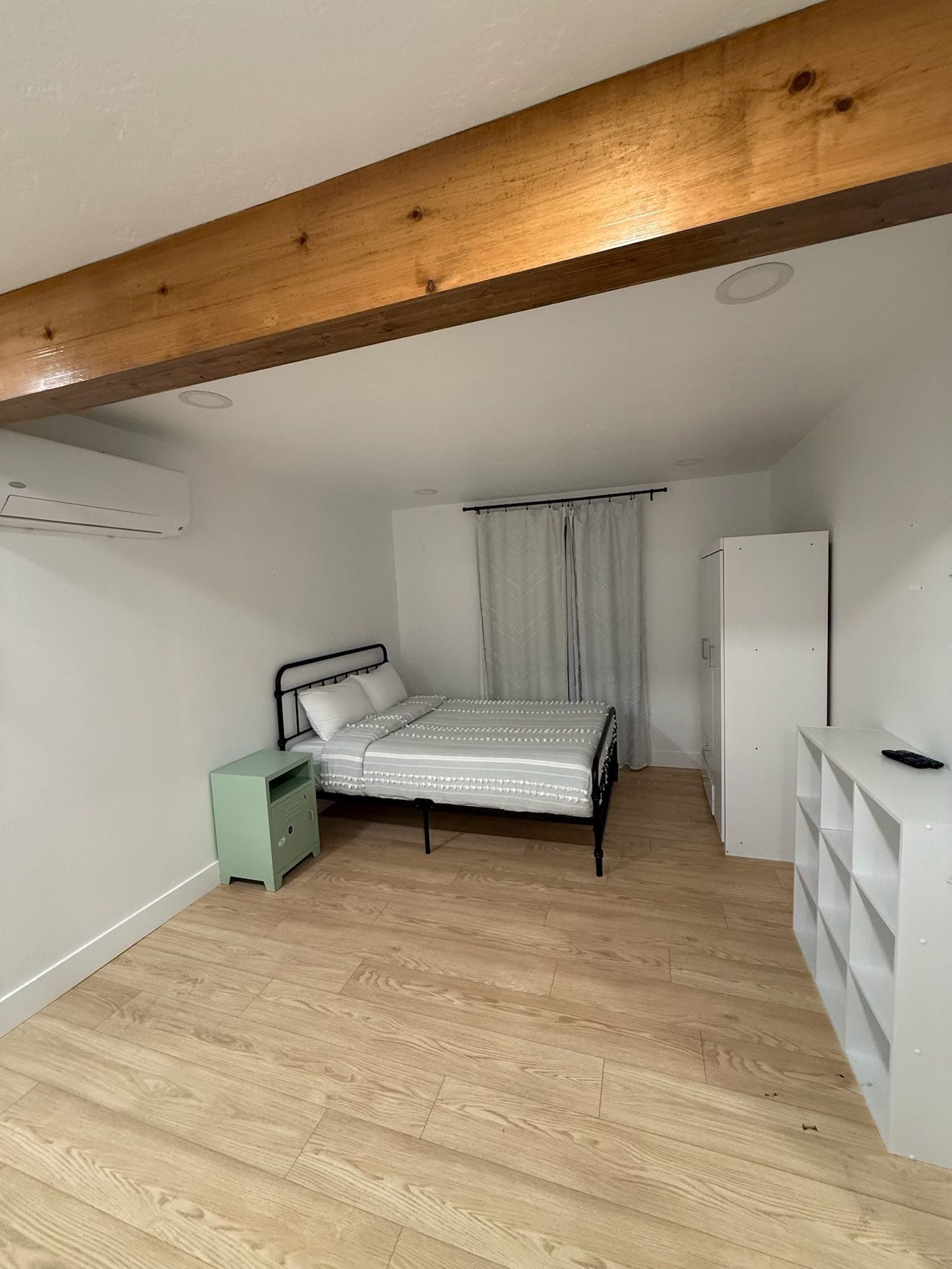 A bedroom with a bed, a nightstand, a wardrobe, and a desk.