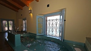 A spa area with a hot tub, wooden flooring, and a window with decorative iron bars. - Vice King's Palace (Lezzeno)