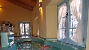 A spa area with a large hot tub, wooden ceiling, and windows with curtains. - Vice King's Palace (Lezzeno)