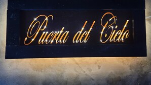 Ein Schild mit dem Schriftzug 'Puerta del Cielo' vor dunklem Hintergrund.