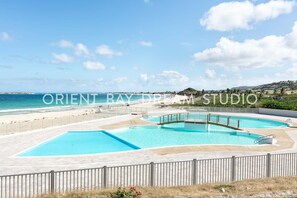 A pool area with a view of the beach and ocean.