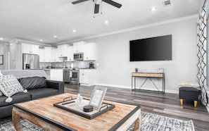 Una sala de estar moderna con un sofá, una mesa de centro y un televisor montado en la pared.