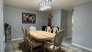 A dining room with a wooden table and chairs, a chandelier, a patterned rug, and a framed picture on the wall. - Cozy getaway in the Poconos — 5minutes away from all your favorite attractions ! (Stroudsburg)