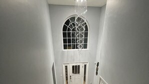 A staircase with a patterned carpet leading to a door with a decorative glass window above. - Cozy getaway in the Poconos — 5minutes away from all your favorite attractions ! (Stroudsburg)